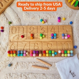 Puede incluir: Tablero de números de madera con números tallados del 0 al 10, cada ranura llena de bolas de fieltro de colores. Incluye dos palitos de madera y una pequeña bolsa blanca con texto. Juguete educativo.
