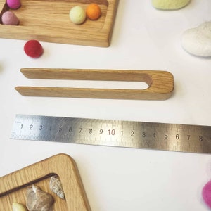 Puede incluir: Pinzas de madera con mango redondeado, que miden aproximadamente 25 cm de largo. Las pinzas est&aacute;n hechas de madera natural y tienen un acabado liso.