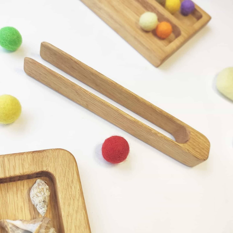 Puede incluir: Pinzas de madera para recoger objetos peque&ntilde;os, como bolas de fieltro. Las pinzas est&aacute;n hechas de madera natural y tienen un acabado liso.
