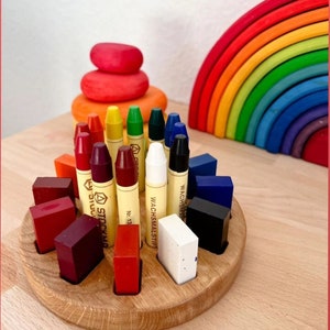 May include: A wooden tray with a circular base holds a set of 12 colorful crayons and 12 corresponding colored blocks. The crayons are labeled "Wachsmalstift" and "No. 13".