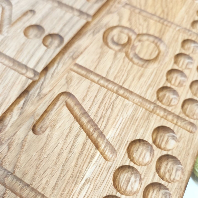 May include: Close-up of wooden game boards with carved numbers and dots. The boards are made of light-colored wood, with the numbers and dots carved into the surface. The design is simple and elegant.
