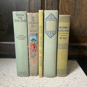 May include: A collection of five vintage paperback books with green and yellow covers. The titles include "Little Old New York", "The Poor House Boy", "The Story of Patsy", "Ben Hur", and "The Totem of Black Hawk".