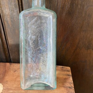 Botella de agua india. Botella verde con cabeza de indio de Healy & Bigelow. Agwa de los indios. Antigua botella de los nativos americanos. imagen 1