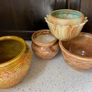 Könnte beinhalten: Vier Keramik-Blumentöpfe in verschiedenen Farben und Designs. Die Töpfe sind braun, grün und gelb mit verschiedenen Mustern und Texturen.