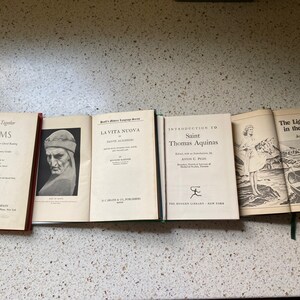 K&ouml;nnte beinhalten: Eine Sammlung von f&uuml;nf alten gebundenen B&uuml;chern mit verschiedenen Titeln. Die B&uuml;cher sind horizontal auf einer hellbraunen Oberfl&auml;che angeordnet. Die Titel der B&uuml;cher lauten "Let's Read Together Poems", "La Vita Nuova", "Introduction to Saint Thomas Aquinas" und "The Light in the Tower".