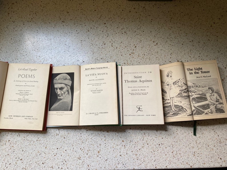 K&ouml;nnte beinhalten: Eine Sammlung von f&uuml;nf alten gebundenen B&uuml;chern mit verschiedenen Titeln. Die B&uuml;cher sind horizontal auf einer hellbraunen Oberfl&auml;che angeordnet. Die Titel der B&uuml;cher lauten "Let's Read Together Poems", "La Vita Nuova", "Introduction to Saint Thomas Aquinas" und "The Light in the Tower".