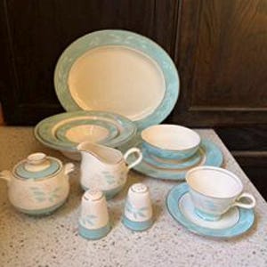 May include: A vintage porcelain dinner service with a light blue and cream floral pattern. The set includes an oval platter, bowls, a creamer, a sugar bowl, salt and pepper shakers, and a teacup with a saucer.
