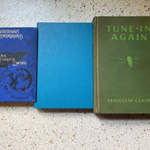 K&ouml;nnte beinhalten: Drei antike gebundene B&uuml;cher mit blauen, gr&uuml;nen und gr&uuml;nen Einb&auml;nden. Das Buch links tr&auml;gt den Titel "Mrs. Overtheway's Remembrances" und den Autor "Juliana Horatia Ewing" mit Illustrationen. Das mittlere Buch hat einen einfarbigen blauen Einband. Das Buch rechts tr&auml;gt den Titel "Tune-In Again" und den Autor "Malcolm Claire".