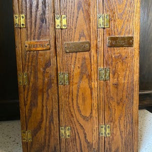 Puede incluir: Un organizador de madera de tres paneles con acabado de veta natural y bisagras de latón. Cada panel incluye una placa de identificación rectangular de latón con el texto grabado INSURE, RECEIPT y MISC, fijada con pequeños tornillos.
