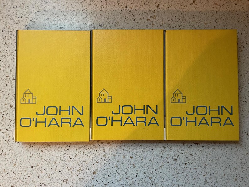 May include: Three yellow hardcover books with the title "JOHN O'HARA" and a small house icon on the front cover.