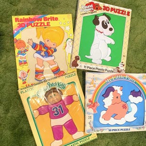 Puede incluir: Cuatro rompecabezas 3D de plástico vintage con Rainbow Brite, Pound Puppies, Cabbage Patch Kids y My Little Pony. Cada caja muestra el personaje, el título y el número de piezas, incluyendo un rompecabezas de Pound Puppies de 11 piezas y uno de 10.