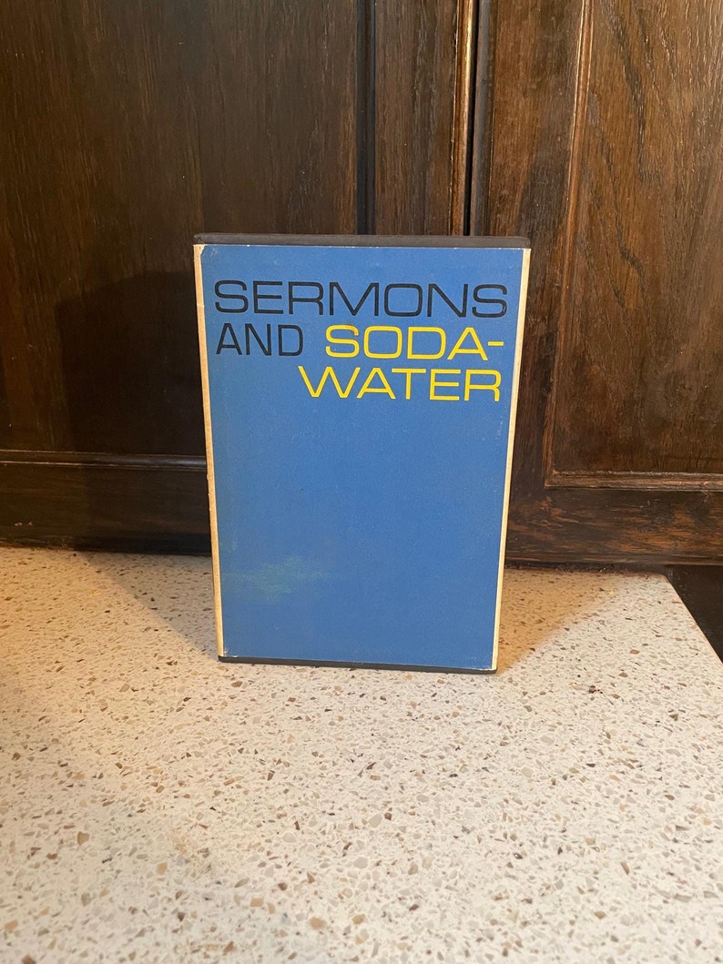 May include: A blue book with the title "SERMONS AND SODA WATER" in black and yellow lettering.