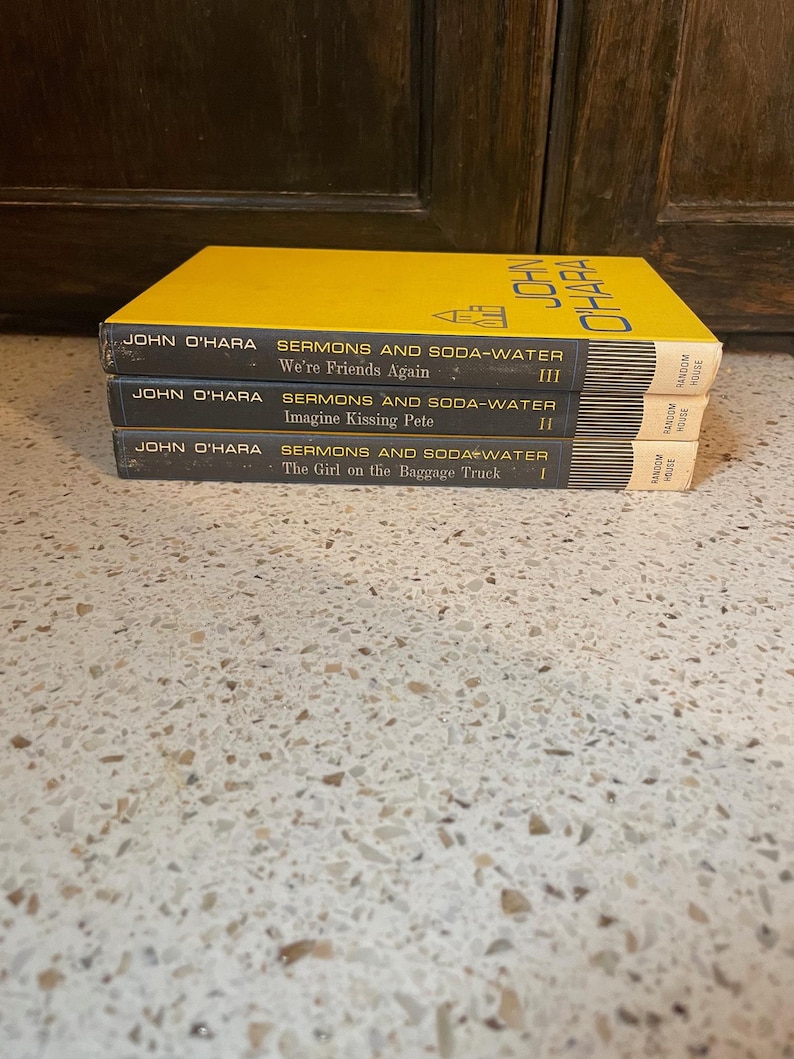 May include: A stack of three yellow paperback books with the title "Sermons and Soda-Water" by John O'Hara. The books are numbered I, II, and III. The books are published by Random House.