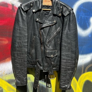 May include: Black leather motorcycle jacket with a zipper closure, a belt, and a quilted lining. The jacket has a label that reads "Excelled" and "Genuine Leather".