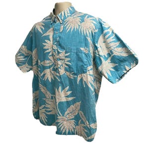 May include: A blue short-sleeved button-down shirt with a white floral print.
