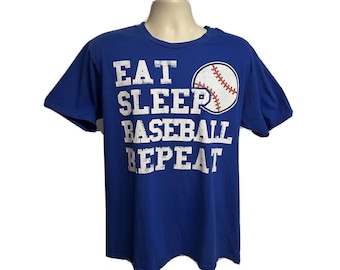 Könnte beinhalten: Ein königsblaues T-Shirt mit einer weißen Grafik, auf der "Eat Sleep Baseball Repeat" steht, und einer Baseball-Grafik.