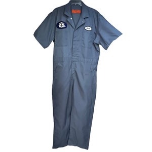 May include: A gray short-sleeved jumpsuit with a patch on the left chest and a name tag on the right chest. The name tag says "Kevin".