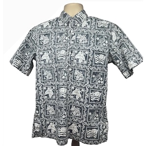 Puede incluir: Camisa de manga corta con botones y un estampado repetido de motivos florales blancos, pájaros y banderas sobre un fondo gris oscuro. La camisa tiene un cuello clásico y cierre de botones.