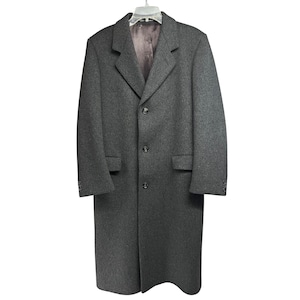 May include: A charcoal gray overcoat with a notched collar, three-button closure, and two front pockets. The coat is hanging on a clear hanger. The coat has a classic, tailored design.
