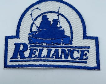 May include: Blue and white embroidered patch featuring the word "RELIANCE" and a silhouette of two people in a boat.