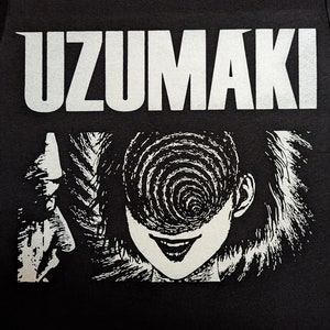 May include: Black t-shirt with a white graphic print of the word "UZUMAKI" and a black and white illustration of a woman with a spiral in her eye.