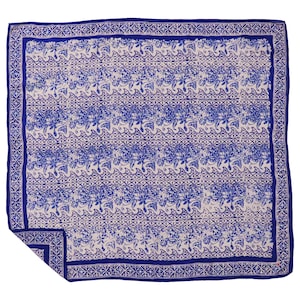 May include: A square, blue and white patterned scarf. The scarf features a repeating floral and geometric design in blue on a white background. A solid blue border frames the edges, with a detailed pattern.