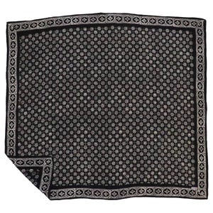 May include: A black and white square scarf with a repeating starburst pattern. The border features a decorative design. The scarf is folded at the corner, showcasing the intricate details of the fabric.