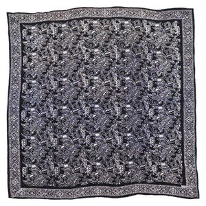 May include: Square black and white patterned scarf. The scarf features a repeating floral design in white against a black background. A geometric border frames the edges. The scarf is likely made of a lightweight fabric.