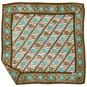 May include: Square patterned scarf with a brown border and a white center. The center features diagonal rows of brown and teal leaf designs. The border has teal diamond shapes and floral patterns. The scarf is folded at the bottom left corner.