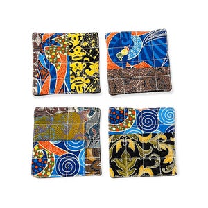 May include: Set of four square fabric coasters. Each coaster features a unique patchwork design with vibrant colors including blue, orange, yellow, and brown. The coasters are quilted with a grid pattern.