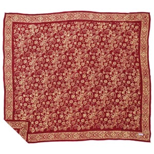 May include: A red textile with a gold floral pattern and a geometric border. The design features swirling vines and heart-shaped leaves. The textile is likely a blanket or throw.