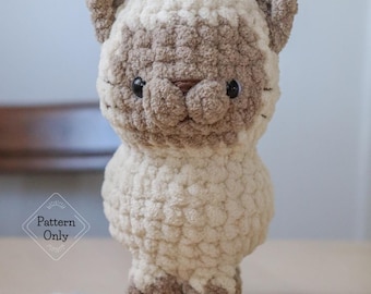 May include: A crocheted cat toy with brown and white fur, standing on a wooden surface with a ball of yarn.