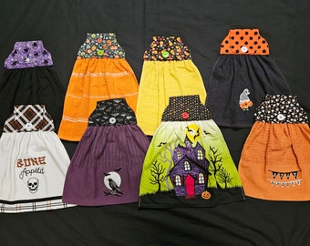 Peut inclure: Huit torchons de cuisine sur le thème d'Halloween avec différents motifs, dont un crâne, une maison hantée, des chauves-souris et des bonbons en forme de maïs. Les torchons sont tous orange, noir, blanc, violet et jaune.