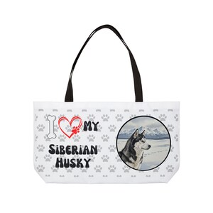 Może przedstawiać: Biała torba typu tote z czarnymi uchwytami. Projekt zawiera ślady łap, serce i napis "I love my Siberian Husky". Okrągły obraz przedstawia husky syberyjskiego w zaśnieżonym krajobrazie.