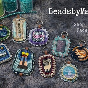 May include: A collection of beaded keychains with various designs and text, including "Breathe" and "I didn't quit today." The keychains are in different shapes and colors, with a leather loop for attachment. The image also includes the text "BeadsbyMsAp" and "Shop now on Facebook!"
