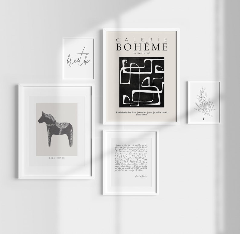 May include: A gallery wall with five framed prints. The prints feature a black and white abstract design, a black and white illustration of a horse, a handwritten note, a simple line drawing of a branch, and the text "breathe".