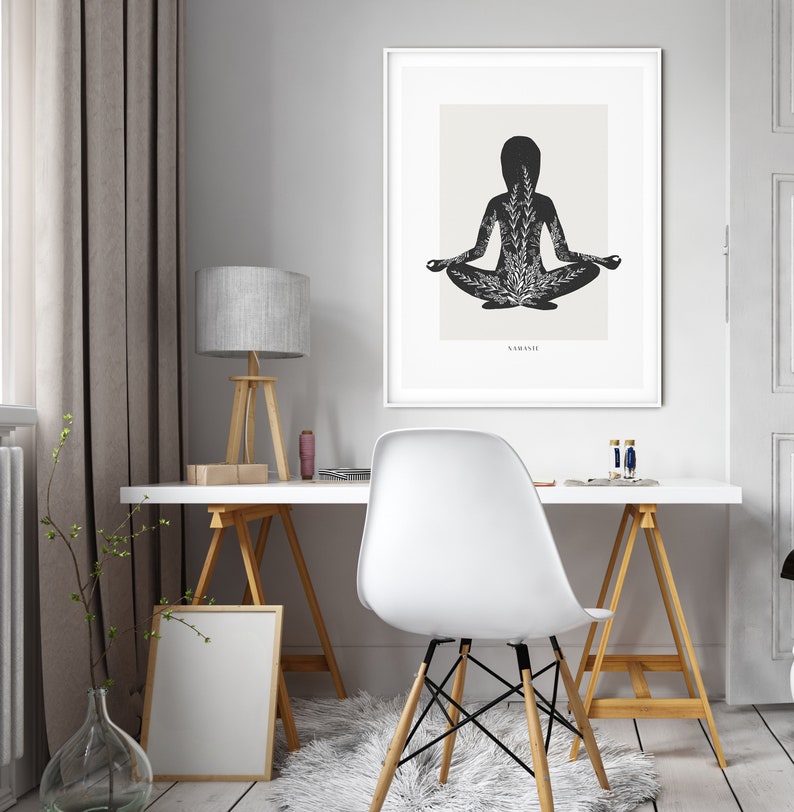 Puede incluir: Una ilustraci&oacute;n en blanco y negro de una persona en una postura de yoga con la palabra "Namaste" en la parte inferior de la imagen. La ilustraci&oacute;n est&aacute; enmarcada y colgada en una pared blanca.