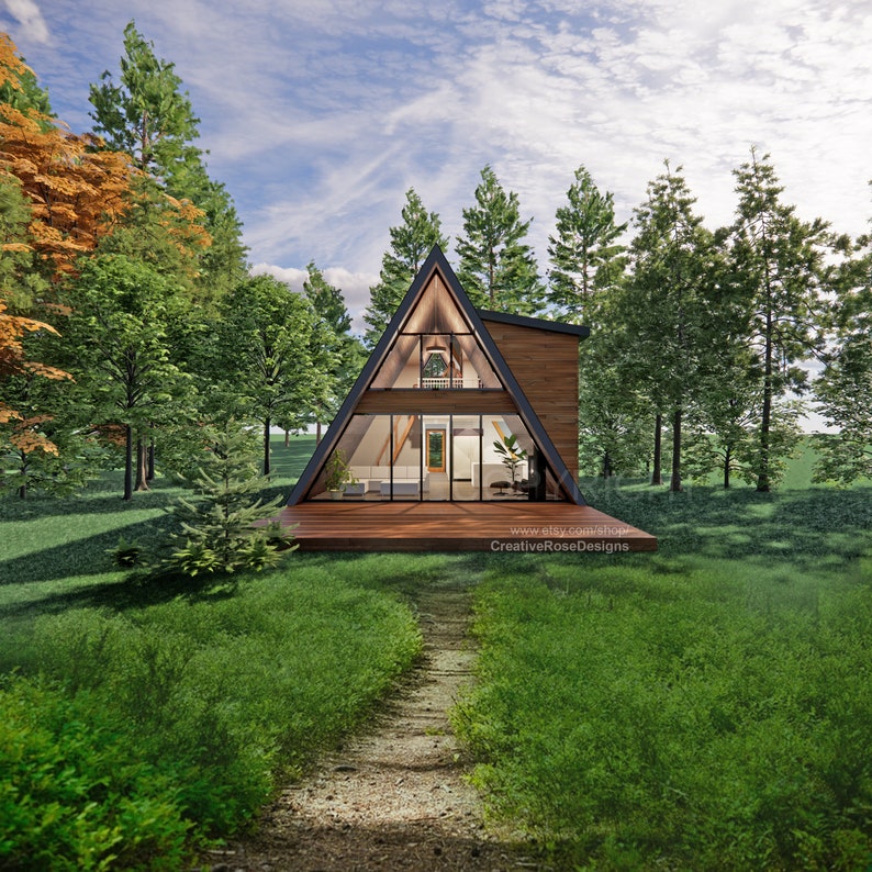 May include: A wooden A-frame cabin with large windows, a deck, and a path leading to it. The cabin is surrounded by trees and green grass.