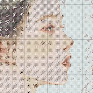 May include: A cross-stitch pattern of a person's face in profile. The design uses a grid of small squares in shades of beige, brown, and purple to create the image. The person's eye, nose, and lips are visible, with the hair on the left side.