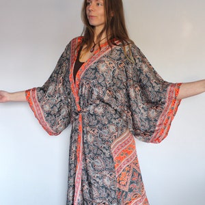 May include: A long, flowing black and orange patterned kimono with a tie belt. The kimono has a floral design with a paisley pattern.