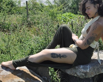 May include: A cream-colored halter top with a tie-back closure paired with olive green leggings featuring side slits. The halter top has a geometric pattern on the front, and the leggings are fitted with a high-waisted design.