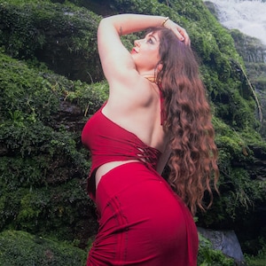 May include: A deep red two-piece outfit consisting of a sleeveless halter-style crop top with side lace-up detailing and a matching high-waisted midi skirt featuring vertical ruched panels with adjustable drawstring ties along the side seams.