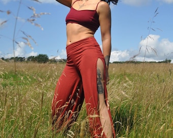 May include: A dark red two-piece set consisting of a cropped camisole top with thin shoulder straps and matching high-waisted wide-leg pants featuring long vertical side slits that extend from the hip down to the hemline of the garment.