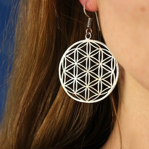 Può includere: Orecchini d'argento con un design geometrico a forma di fiore della vita.