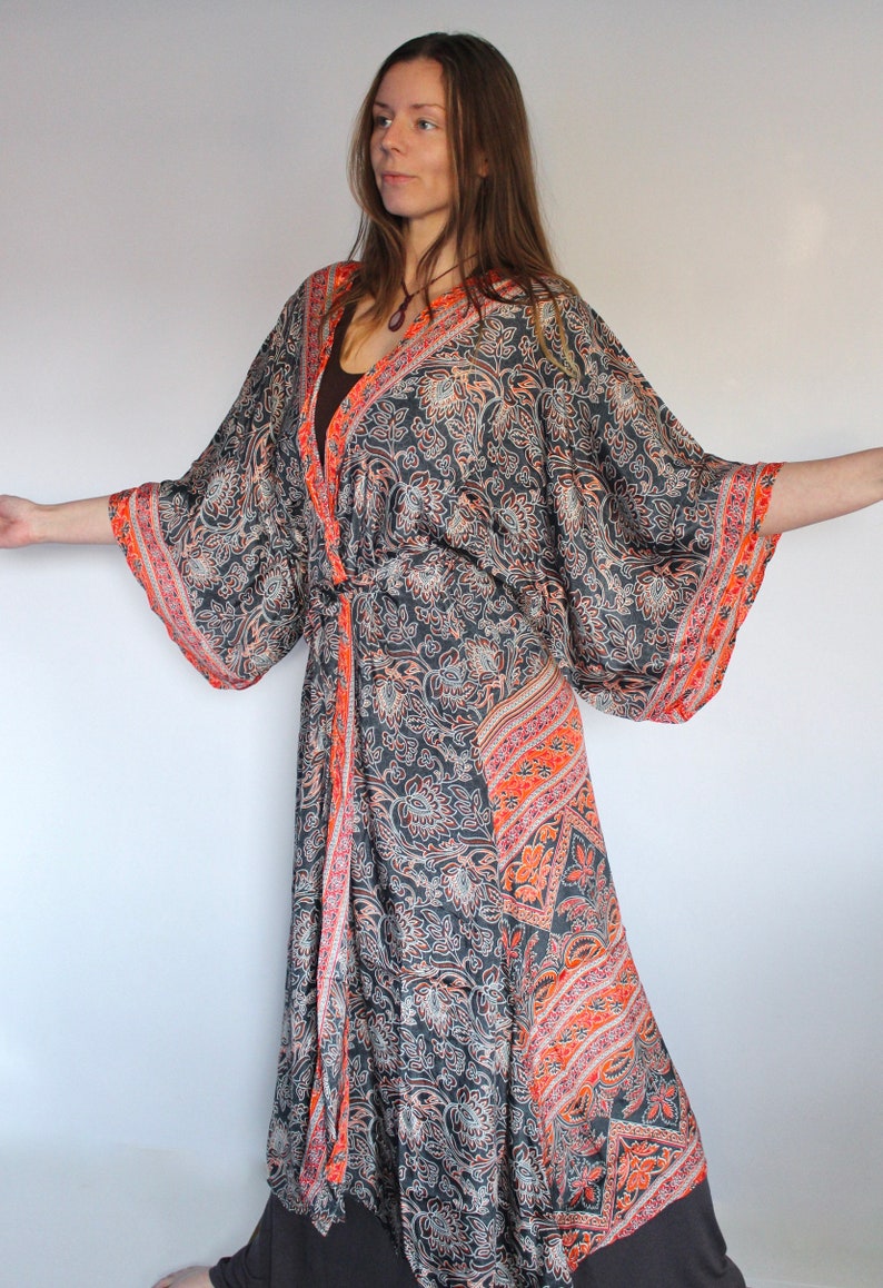 May include: A long, flowing black and orange patterned kimono with a tie belt. The kimono has a floral design with a paisley pattern.