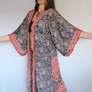 May include: A long, flowing, black and orange patterned kimono with a floral design. The kimono has long sleeves and a wide, open neckline.