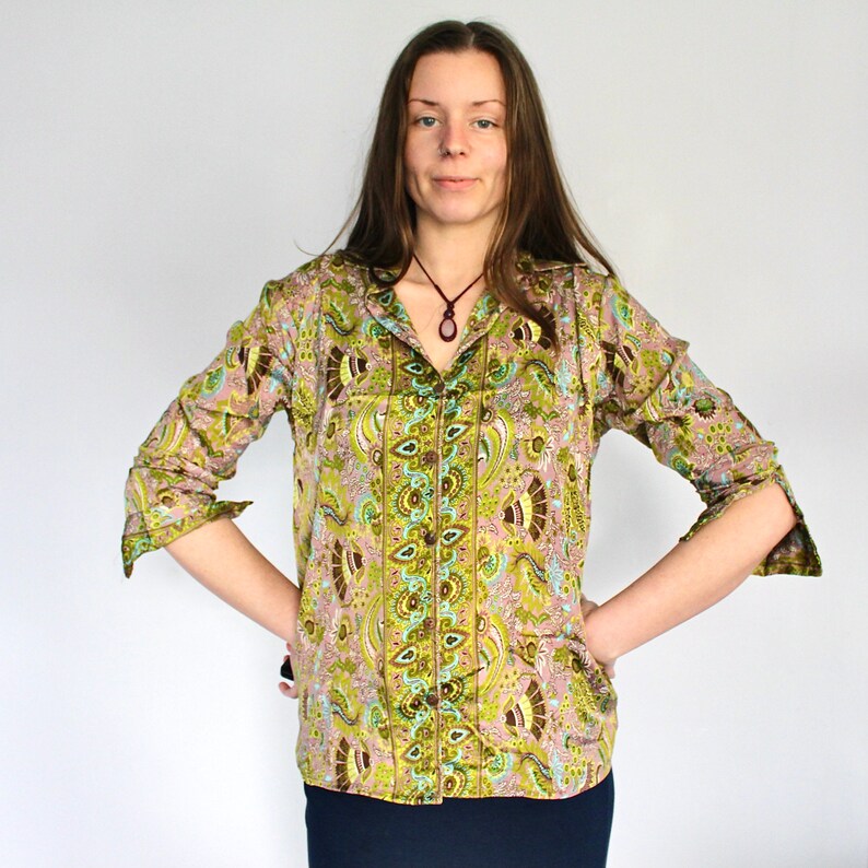 Op de afbeelding: Een groen en bruin paisley-patroon shirt met een knoopsluiting aan de voorkant en lange mouwen. Het shirt heeft een kraag en een donkerbruine ketting.
