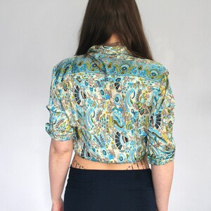 Op de afbeelding: Een blauw en wit paisley-patroon overhemd met lange mouwen en een knoopsluiting.