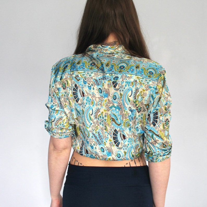 Op de afbeelding: Een blauw en wit paisley-patroon overhemd met lange mouwen en een knoopsluiting.
