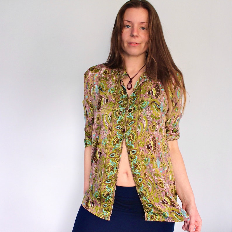 Op de afbeelding: Een lang mouw overhemd met knopen en een paisley print in tinten van groen, bruin en blauw. Het overhemd heeft een kraag en een knoopsluiting aan de voorkant.